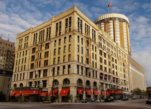 Historic building with ornate architecture, featuring large windows and a modern skyscraper in the background under a cloudy sky.