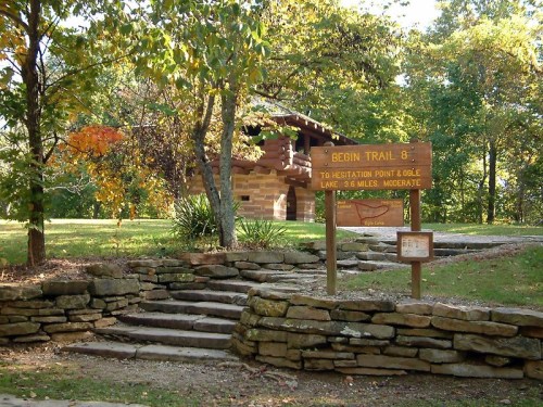 Sign marking the beginning of Trail 8, surrounded by trees and stone steps in a scenic outdoor setting.