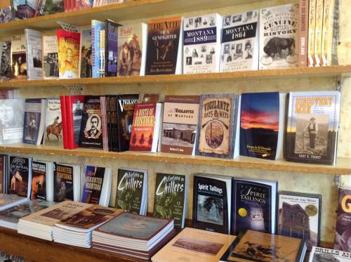 A bookshelf filled with various books on Montana's history, including titles on vigilantes and local legends.