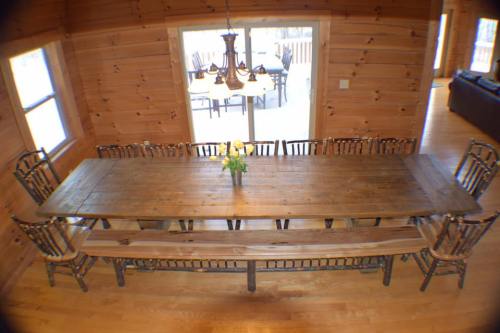 A large wooden dining table with benches and chairs, set in a cozy log cabin with natural light.
