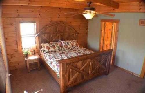 Cozy bedroom with a wooden bed, floral bedding, and rustic decor, featuring a ceiling fan and warm wooden walls.
