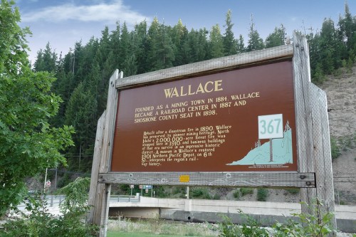 Sign about Wallace, a former mining town, detailing its history and significance as a railroad center and county seat.