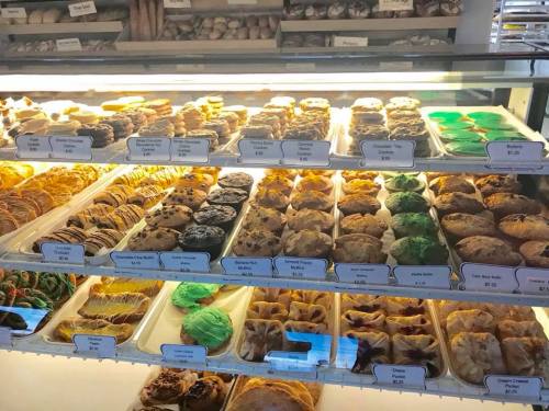A display case filled with various baked goods, including cookies, pastries, and colorful treats.