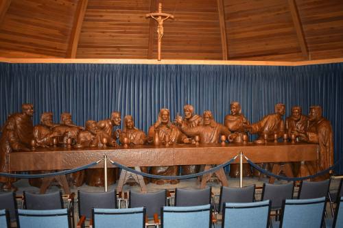A wooden sculpture of the Last Supper, featuring Jesus and his disciples, displayed in a chapel setting.