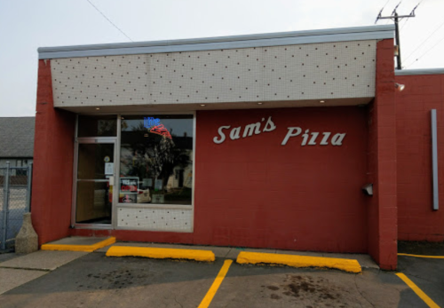 Exterior of Sam's Pizza, featuring a red brick facade and a large sign with the restaurant's name.