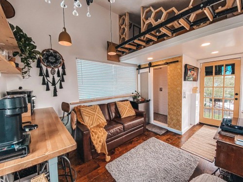 Cozy living space with a brown sofa, wooden shelves, and a bright door, featuring warm decor and natural light.
