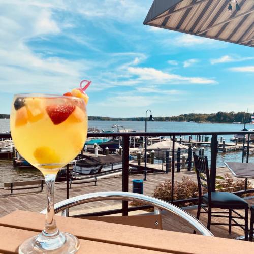 A colorful cocktail with fruit sits on a table overlooking a marina and blue sky.