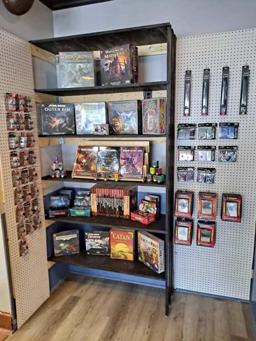 A display shelf filled with various board games, miniatures, and gaming accessories in a store setting.