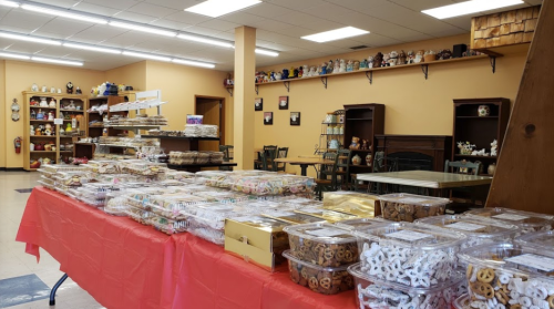 A bright bakery interior with tables filled with various baked goods and treats, showcasing colorful confections and cookies.