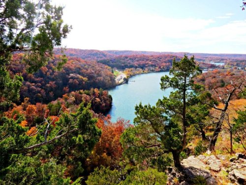 A scenic view of a river winding through colorful autumn foliage and trees from a high vantage point.