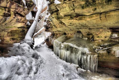 A snowy canyon with icy rock formations and a narrow path winding through the cliffs.