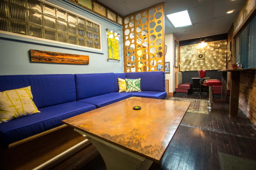 Cozy lounge area with a blue couch, decorative pillows, wooden table, and unique wall art in a stylish interior.