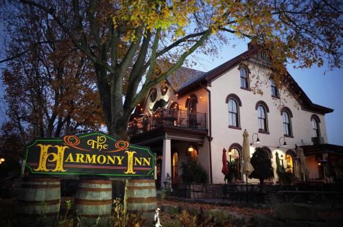 A charming inn with a sign reading "The Harmony Inn," surrounded by autumn trees and outdoor seating.