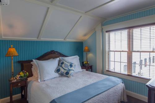 Cozy bedroom with a blue accent wall, a queen bed, decorative pillows, and lamps on wooden nightstands.