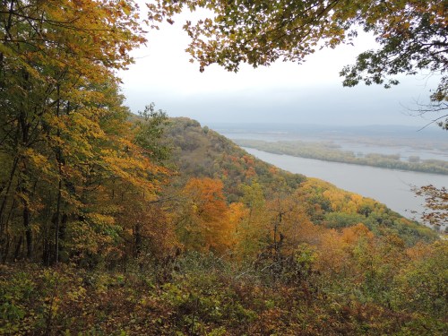A scenic view of a river winding through colorful autumn foliage on a hillside.