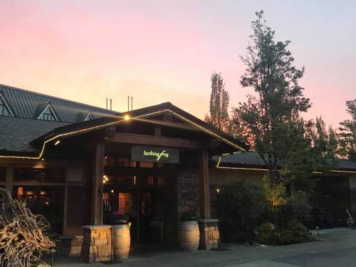 A rustic building with a sign reading "Barking Frog" at sunset, surrounded by trees and warm lighting.