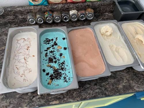 Five ice cream tubs on a counter, featuring flavors like vanilla, mint chocolate chip, and cookies and cream.