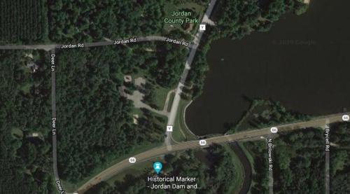 Aerial view of Jordan County Park, featuring roads, a lake, and a historical marker.