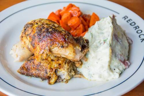 A plate featuring roasted chicken, mashed potatoes, and seasoned carrots.