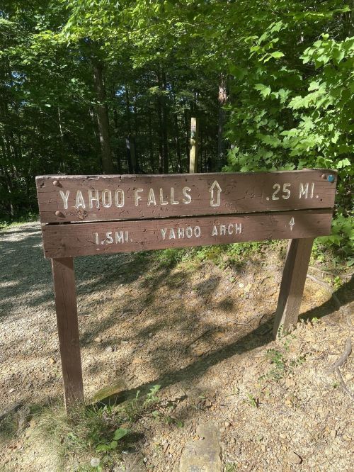 Wooden signpost indicating directions to Yahoo Falls and Yahoo Arch, surrounded by greenery.