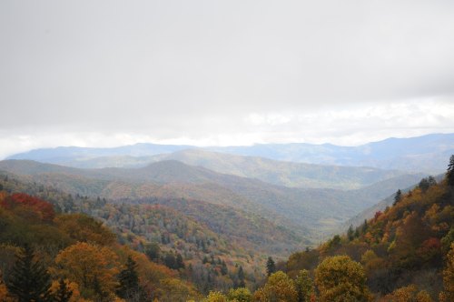 A scenic view of rolling mountains covered in autumn foliage under a cloudy sky.