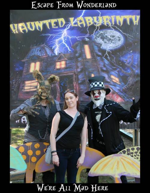 A woman stands between two costumed characters in front of a spooky backdrop with the text "Escape From Wonderland."