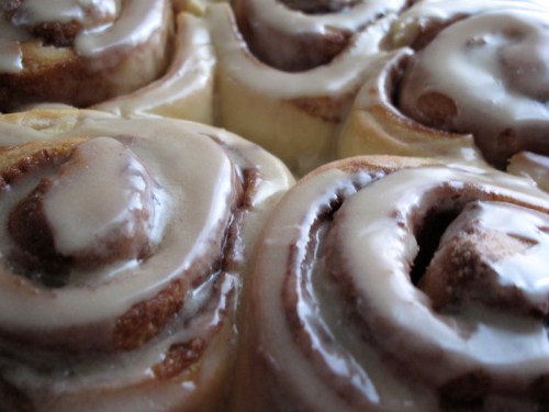 Close-up of freshly baked cinnamon rolls topped with creamy icing.