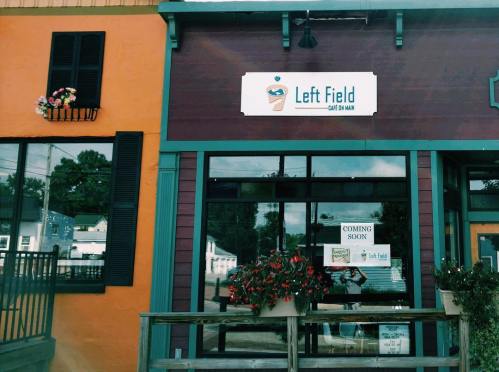 Exterior of a café named "Left Field" with a sign, flower boxes, and a "Coming Soon" banner.