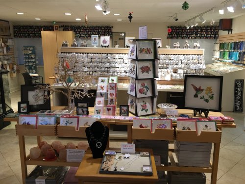 A craft store display featuring greeting cards, jewelry, and decorative items, with colorful beads in the background.