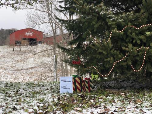 A snowy scene with a decorated tree, gifts, and a sign wishing "Merry Christmas" and "Happy Holidays" in the background.