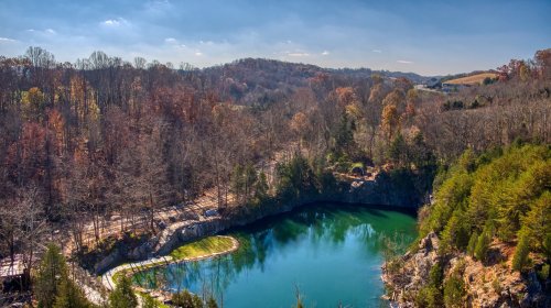 A serene, turquoise lake surrounded by autumn-colored trees and rocky cliffs under a clear blue sky.