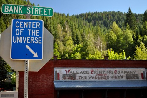 A street sign for Bank Street points to "Center of the Universe," with a historic building in the background.