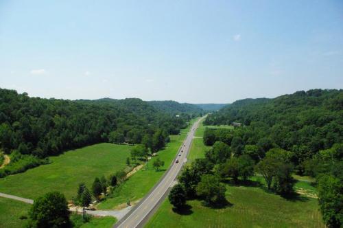 A scenic view of a winding road through lush green hills and fields under a clear blue sky.