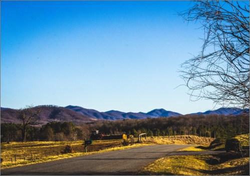 A scenic view of a winding road leading towards distant mountains under a clear blue sky.
