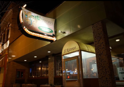 A brightly lit restaurant exterior at night, featuring a sign that reads "Il Ritrovo" and a welcoming entrance.