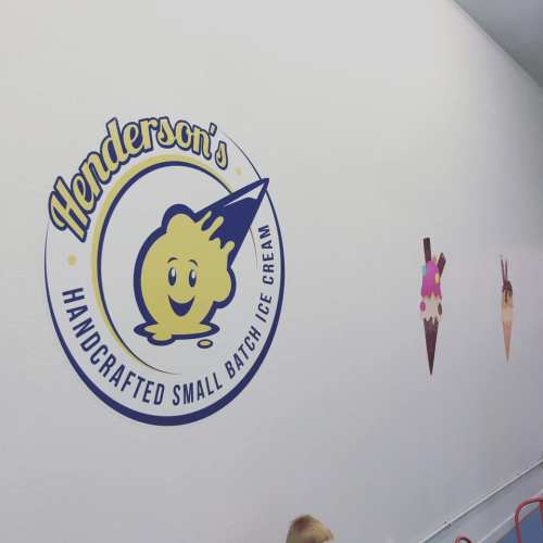 Sign for Henderson's Handcrafted Small Batch Ice Cream on a wall, with ice cream cone decorations nearby.