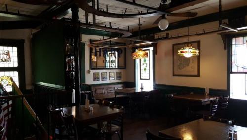 Cozy restaurant interior with wooden tables, stained glass lamps, and vintage decor on the walls.