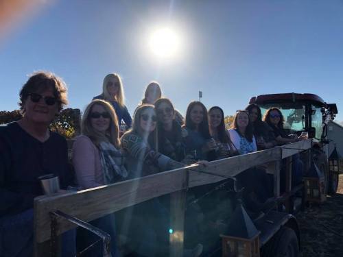 A group of people sitting on a trailer under the sun, enjoying a day outdoors.