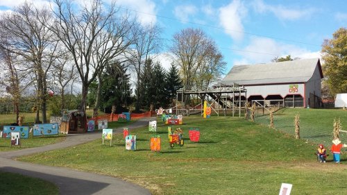 A farm scene with colorful decorations, a barn, and trees under a blue sky with scattered clouds.
