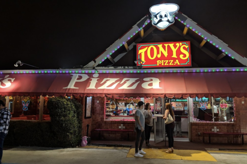 A brightly lit pizza restaurant named "Tony's Pizza" with colorful lights and a welcoming entrance at night.