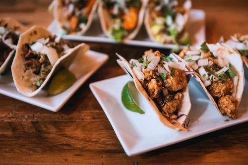 A close-up of delicious tacos filled with meat, onions, and cilantro, served on white plates with lime wedges.