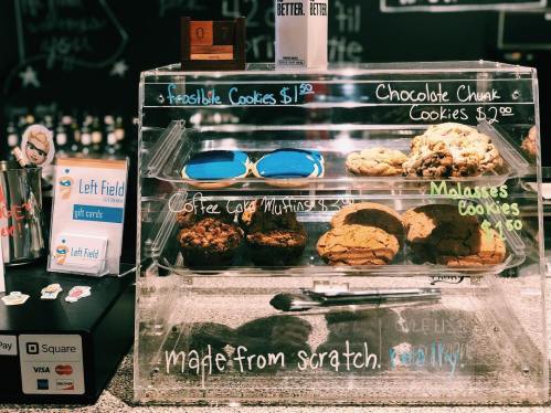 Display case with assorted cookies and muffins, including chocolate chunk and molasses, with prices listed.