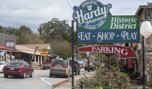 Sign for Hardy, Arkansas, Historic District with directions for dining, shopping, and parking, alongside a busy street.