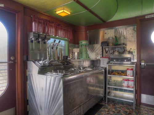 Vintage diner kitchen with stainless steel equipment, a green mixer, and shelves of ingredients and utensils.