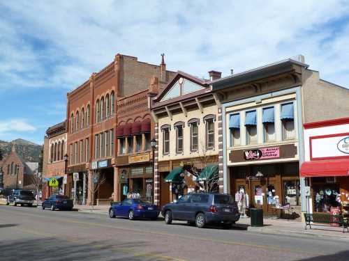 Historic buildings line a street, featuring shops and restaurants under a clear blue sky.