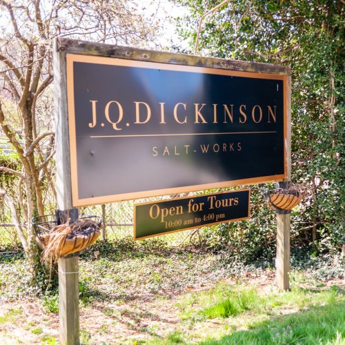Sign for J.Q. Dickinson Salt-Works, stating "Open for Tours" from 10:00 AM to 4:00 PM, surrounded by greenery.