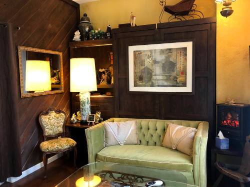 A cozy living room with a green tufted sofa, decorative lamps, and a framed artwork on a wooden wall.