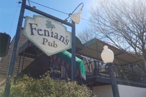 Sign for Fenian's Pub with outdoor seating area and trees in the background on a sunny day.