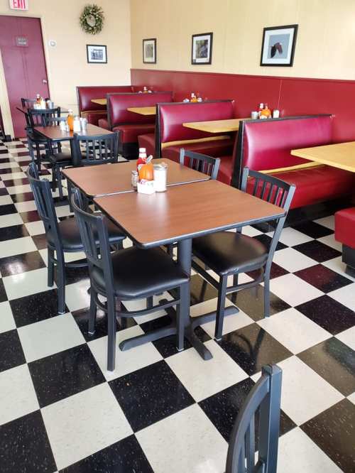 Interior of a diner with red booths, black and white checkered floor, and tables set for dining.
