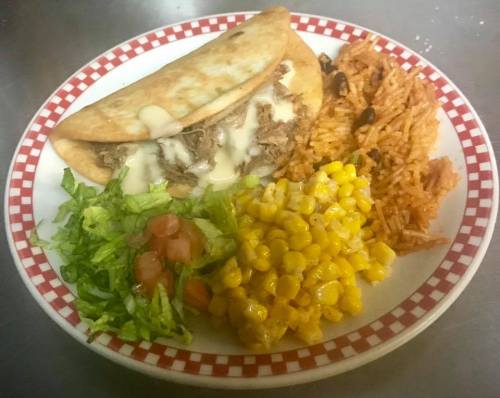 A plate of food featuring a taco with meat and cheese, rice, corn, and a side salad with tomatoes.